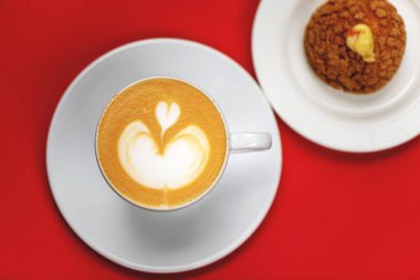 Latte sanat ve choux pasta ile kahve fincanı üst görünümü.