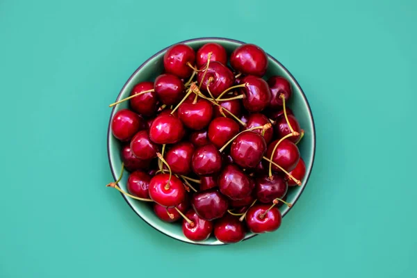 Frische Kirschen in einer Schüssel auf grünem Hintergrund. gesundes Ernährungskonzept — Stockfoto