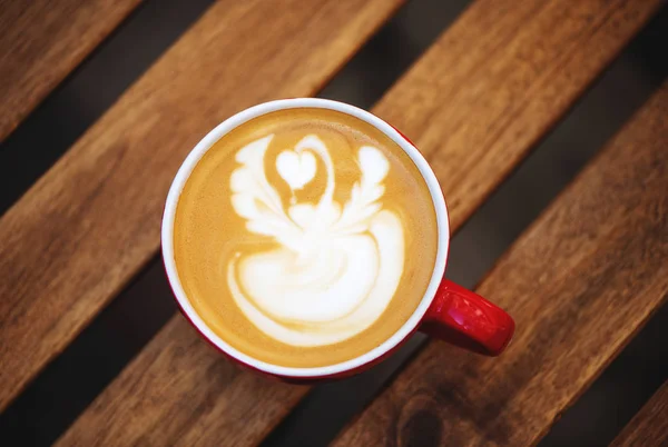 Kopje koffie met latte kunst op houten tafel in café. — Stockfoto