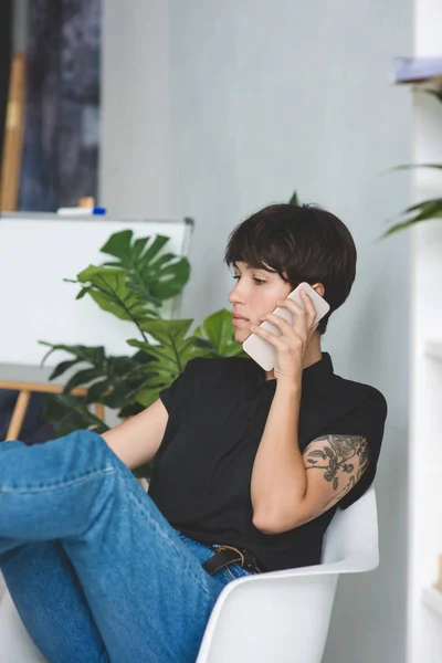 Ofiste oturan telefonda konuşan güzel genç iş kadını. — Stok fotoğraf