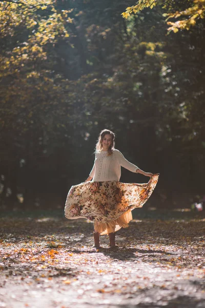 Donna sorridente che balla nel parco autunnale in aumento della luce solare . — Foto Stock