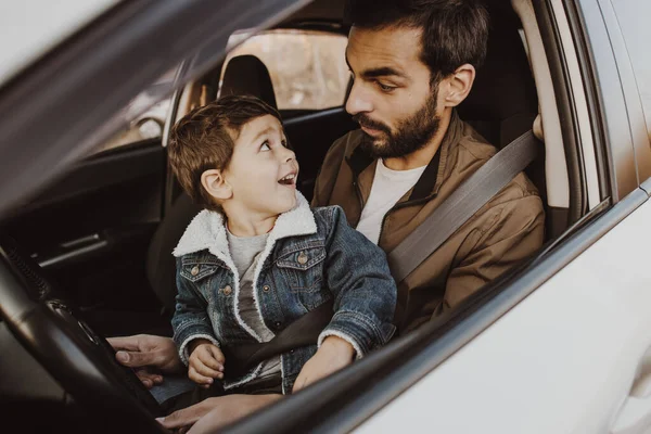 Padre jugando con su hijo en el asiento de los conductores en su coche . — Foto de Stock