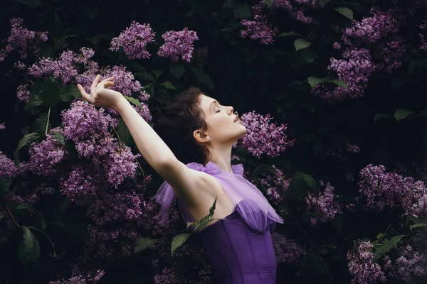 Beautiful woman in garden with blooming lilacs. — Stock Photo, Image