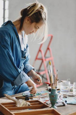 Stüdyoda boyaları palette karıştıran kadın..