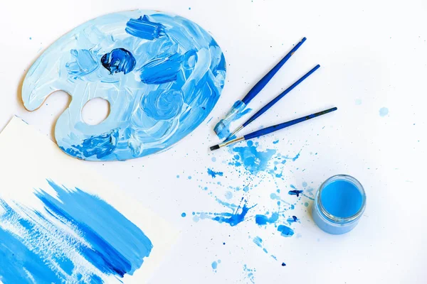 Blå penslar och palett med abstrakt färg. — Stockfoto