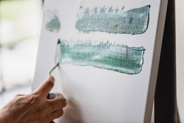 Sanatçı, spatulayla tuval üzerine el resmi yapıyor..