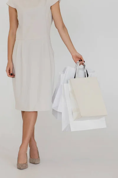 Обрезанное изображение женщины, держащей бумажные пакеты на белом фоне. — стоковое фото