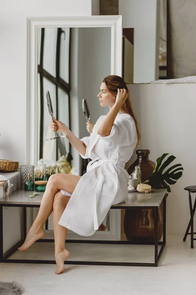 Hermosa mujer de pelo largo disfrutando de maquillaje en la mañana. —  Fotos de Stock