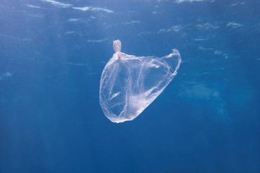 Mavi deniz suyunda yüzen plastik torba. Dünya okyanusu plastikle kirlenmiş. Çevre kirliliği kavramı.