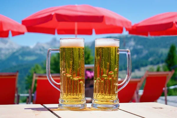 Glass of beer on the table, refreshment on the summer terrace. Alps mountain on the background.