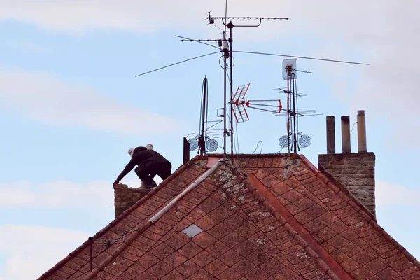 Man renovating an old chimney on the rooftop