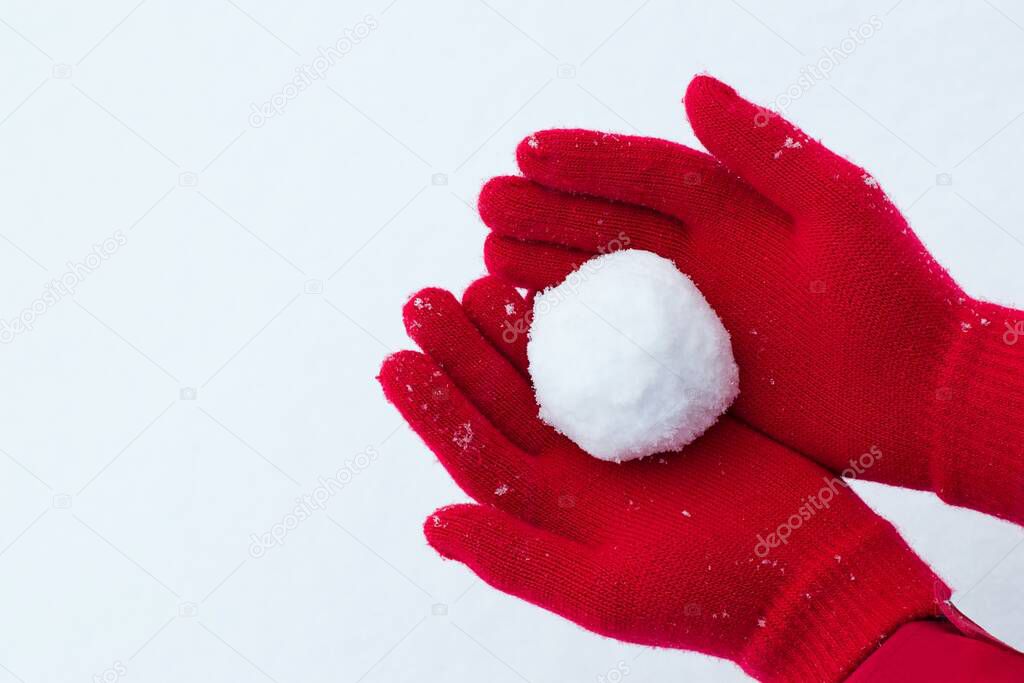 Hands in red gloves holding snowball 