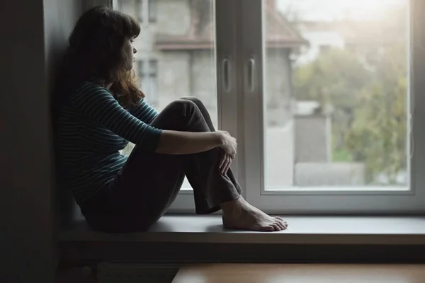 Θλιβερή Νεαρή Γυναίκα Που Κάθεται Στο Παράθυρο Στο Σπίτι Απομονωμένη — Φωτογραφία Αρχείου
