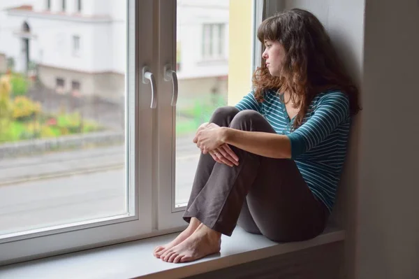 Θλιβερή Νεαρή Γυναίκα Που Κάθεται Στο Παράθυρο Στο Σπίτι Απομονωμένη — Φωτογραφία Αρχείου