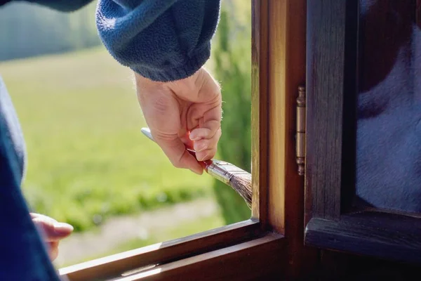 Man painting wooden window, hand detail