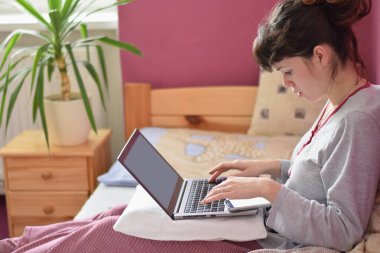 Coronavirus karantinasında bilgisayar üzerinde çalışan genç bir kız öğrenci.