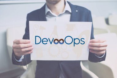 Devops konsepti. Müteahhitler ve operasyon sözcükleri kağıda basıldı ve insanlar bunu ellerinde tutuyorlar. Metnin için boşluk.