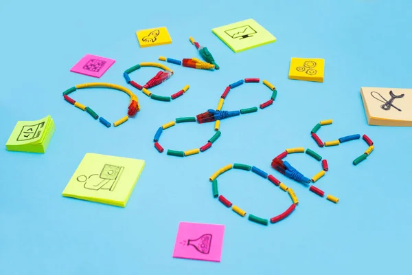 Devops konsepti. Mavi arkaplanda kablolar ve sembollerden oluşturulan geliştiriciler ve işlemler sözcükleri. Metnin için boşluk.