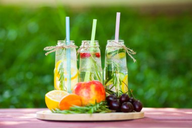 Ahşap arka planda cam şişelerdeki taze detoks sıvıları. Meyveler ve meyveler. Yaşam tarzı, vejetaryen yiyecek ve içecek, sağlık, diyet ve yaz konsepti. Üst Manzara. Kapat.