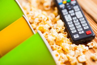 Hafta sonu evde, boş zaman tarzı, TV, fast food konsepti. 3D gözlükler, yeşil kaselerde uzaktan kumanda ve aperatifler: cips, patlamış mısır, ahşap arka planda hamburger. Üst Manzara. Kapat.