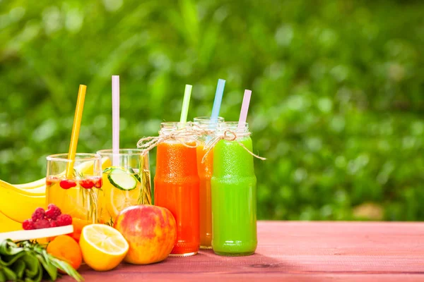 Ahşap arka planda cam şişelerdeki taze detoks sıvıları. Meyveler ve meyveler. Yaşam tarzı, vejetaryen yiyecek ve içecek, sağlık, diyet ve yaz konsepti. Üst Manzara. Kapat..