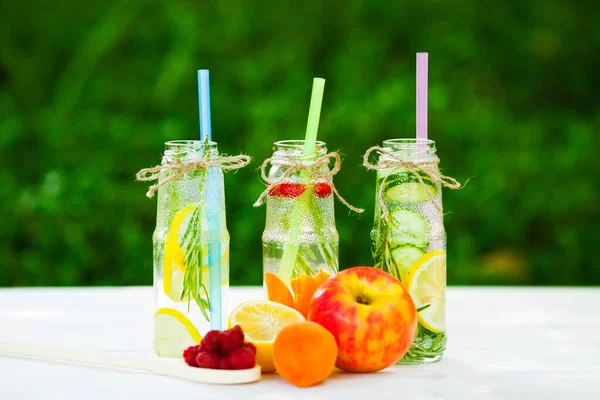 Ahşap arka planda cam şişelerdeki taze detoks sıvıları. Meyveler ve meyveler. Yaşam tarzı, vejetaryen yiyecek ve içecek, sağlık, diyet ve yaz konsepti. Üst Manzara. Kapat..