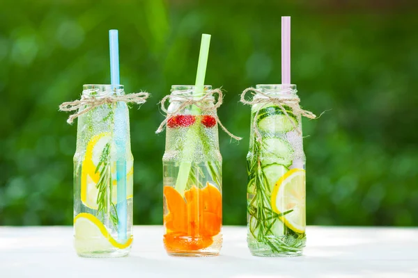 Ahşap arka planda cam şişelerdeki taze detoks sıvıları. Meyveler ve meyveler. Yaşam tarzı, vejetaryen yiyecek ve içecek, sağlık, diyet ve yaz konsepti. Üst Manzara. Kapat..