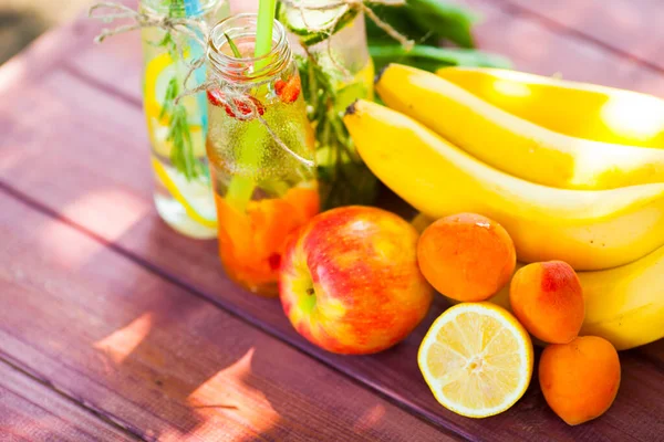 Ahşap arka planda cam şişelerdeki taze detoks sıvıları. Meyveler ve meyveler. Yaşam tarzı, vejetaryen yiyecek ve içecek, sağlık, diyet ve yaz konsepti. Üst Manzara. Kapat.