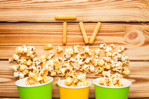 Hafta sonu evde, boş zaman tarzı, TV, fast food konsepti. 3D gözlükler, yeşil kaselerde uzaktan kumanda ve aperatifler: cips, patlamış mısır, ahşap arka planda hamburger. Üst Manzara. Kapat.