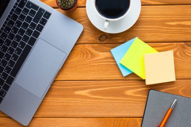 Laptop, beyaz kahve, kaktüs, abur cubur ve parlak ahşap arka planda bir defter. İş, ofis, eğitim, planlama konsepti. Üst Manzara. Kapat..