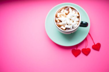 Taze demlenmiş kahve, marşmelov, donut ve pembe arka planda tatlılar. Kurdeleli ve kalpli hediyeler. Üst Manzara. Metnin için boşluk.