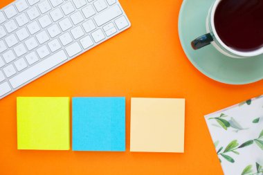 Renkli çıkartmalar, beyaz klavye, defter ve atıştırmalıklar. Ofis masası, masa ve farklı nesneler. Çalışma süreci. Eğitim, iş konsepti.