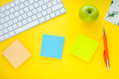 Renkli çıkartmalar, beyaz klavye, defter ve atıştırmalıklar. Ofis masası, masa ve farklı nesneler. Çalışma süreci. Eğitim, iş konsepti.