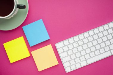 Renkli çıkartmalar, beyaz klavye, defter ve atıştırmalıklar. Ofis masası, masa ve farklı nesneler. Çalışma süreci. Eğitim, iş konsepti.