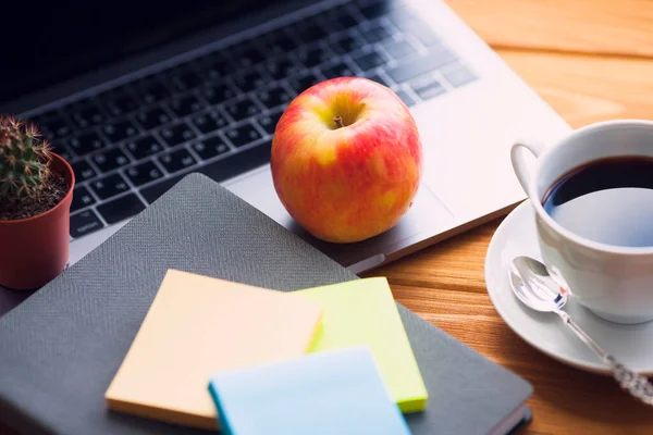 Laptop, beyaz kahve, kaktüs, abur cubur ve parlak ahşap arka planda bir defter. İş, ofis, eğitim, planlama konsepti. Üst Manzara. Kapat..