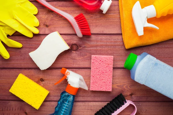 Ahşap arka planda temizlik ürünleri var. Plastik şişeler, deterjan ve fırçalar. Hizmet kavramı. Üst Manzara. Kapat..