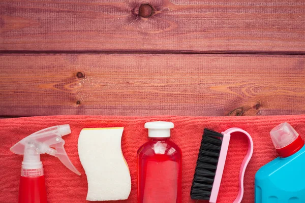 Set of cleaning products on the wooden background. Plastic bottles, detergent and brushes. Service concept. Top view. Close up.