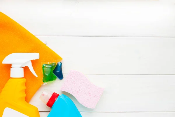 Set of cleaning products on the wooden background. Plastic bottles, detergent and brushes. Service concept. Top view. Close up.