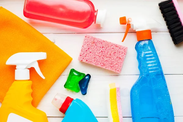 Ahşap arka planda temizlik ürünleri var. Plastik şişeler, deterjan ve fırçalar. Hizmet kavramı. Üst Manzara. Kapat..