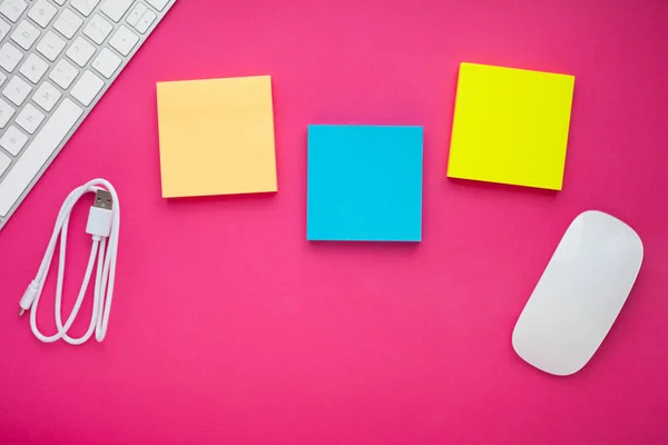 Renkli çıkartmalar, beyaz klavye, defter ve atıştırmalıklar. Ofis masası, masa ve farklı nesneler. Çalışma süreci. Eğitim, iş konsepti.