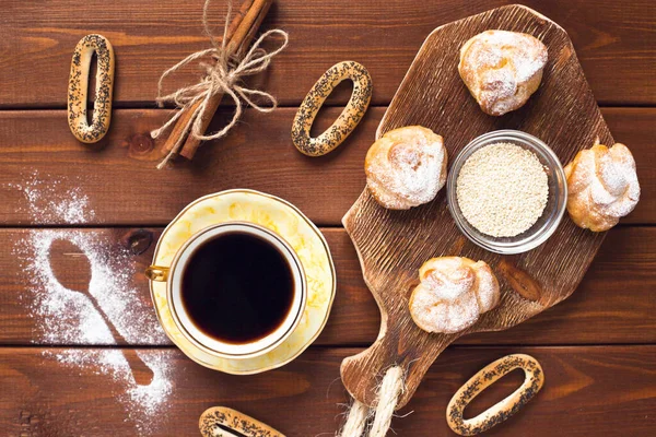 Güzel fırın ürünleri ve bir fincan kaliteli çay. Tahta arka planda kahvaltılık yemeğin düz kompozisyonu yatıyordu. Yemek, mola, yemek pişirme, yaşam tarzı konsepti. Üst Manzara. Kapat..