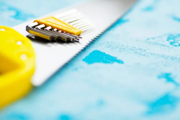 Mavi taş arka planda inşaat malzemeleri. Çekiç, vida, testere, sarı bant ve diğer küçük tamir aletleri. Üst Manzara. Kapat.. 