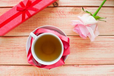 Kahvaltı ahşap masada. Bir fincan çay, çörek ve çiçek. Kapatın. Üst görünüm.