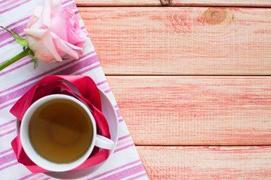 Kahvaltı ahşap masada. Bir fincan çay, çörek ve çiçek. Kapatın. Üst görünüm.