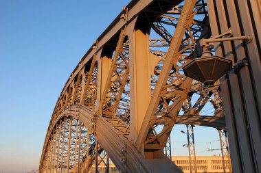 Kemerli tarlaların, desteklerin ve tribünlerin yakın çekimleri, uçaklardaki perçinler. Gün batımından gelen turuncu renk. (Büyük Köprü Peter. Yılların inşaatı 1908-1911)