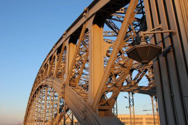 Kemerli tarlaların, desteklerin ve tribünlerin yakın çekimleri, uçaklardaki perçinler. Gün batımından gelen turuncu renk. (Büyük Köprü Peter. Yılların inşaatı 1908-1911)