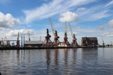 İskele vinçlerindeki sudan gökyüzüne, musluğa ve bulut yansımalarına bak