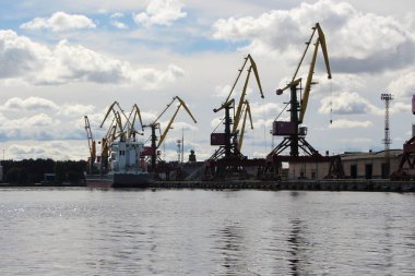 İskele vinçlerindeki sudan gökyüzüne, musluğa ve bulut yansımalarına bak