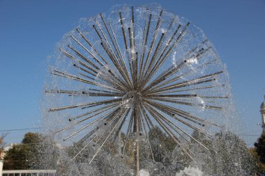 Küre şeklinde bir çeşmeye yakın çekim yap ve gökyüzüne doğru sıçra.