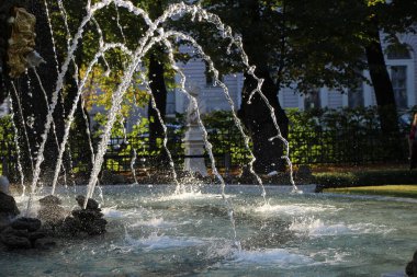 Fıskiyelerin yakın çekim fıskiyeleri ve sonbahar şehir parkındaki günbatımının ışınları.